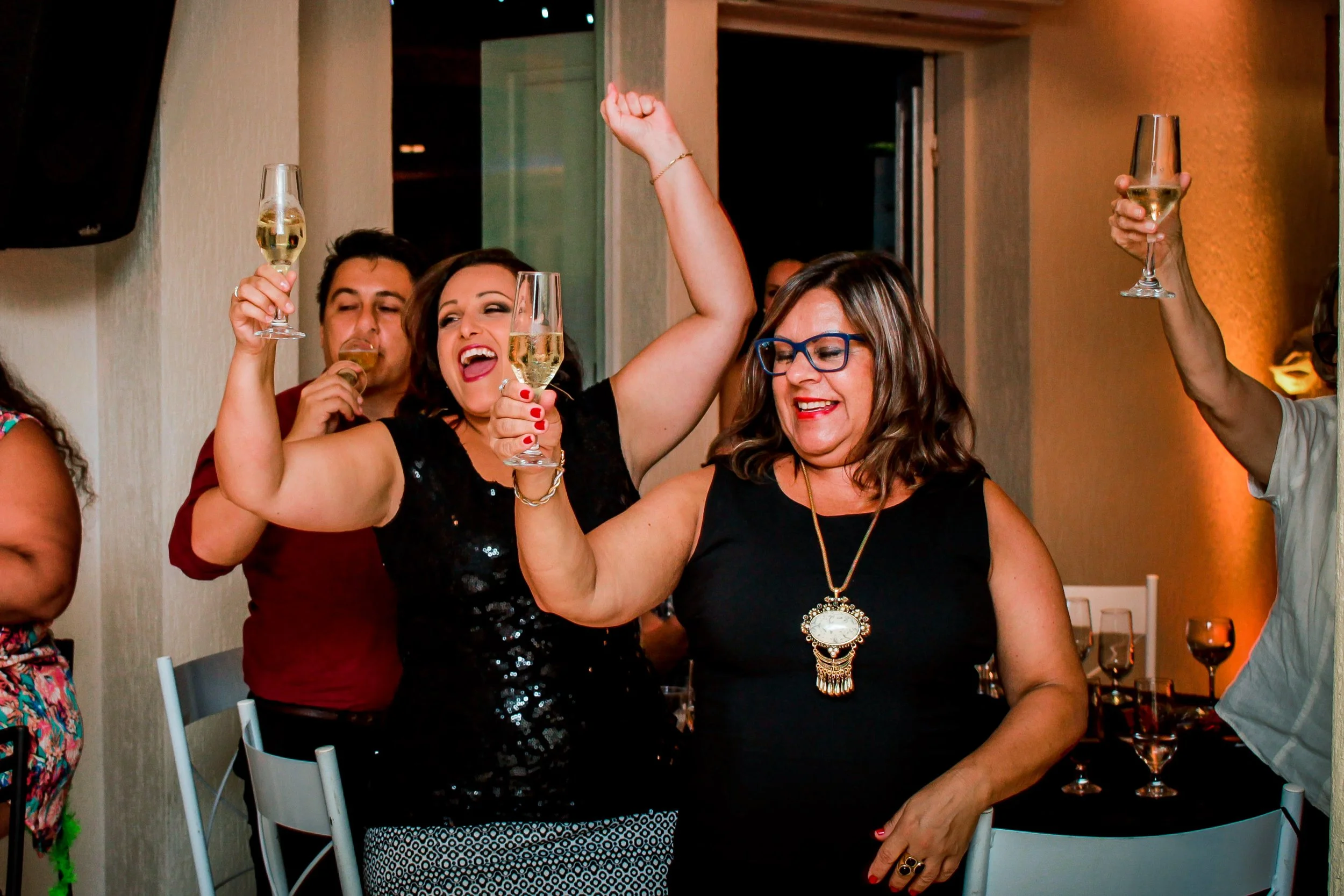 Mulheres celebrando com taças de champagne em uma festa, sorrindo e se divertindo.