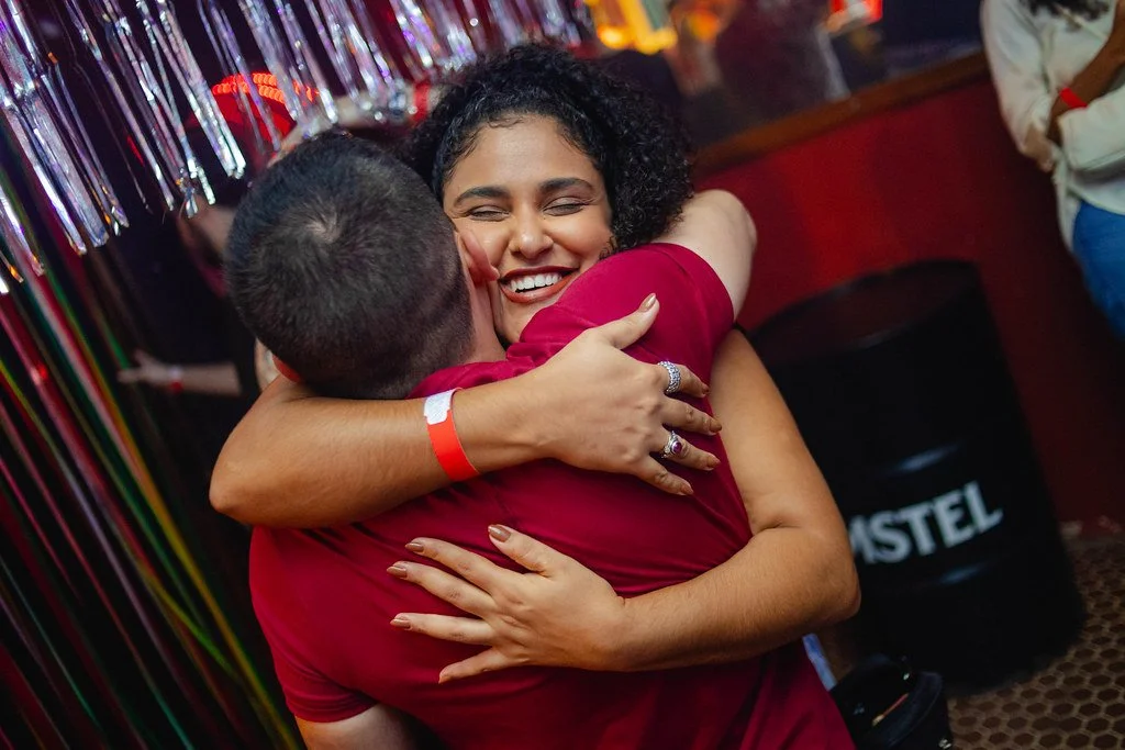 Homem e mulher se abraçando em comemoração, sorrindo em um ambiente festivo