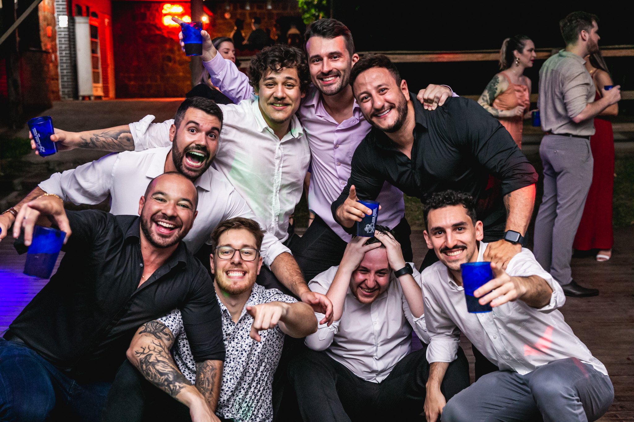 Grupo de amigos sorrindo e brindando em festa no bar ou balada à noite.