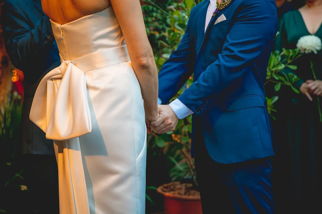 Casal de noivos segurando as mãos durante a cerimônia de casamento.