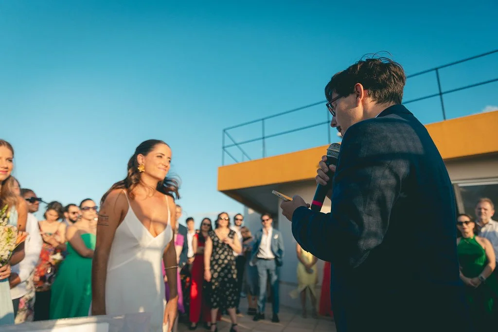 Casal de pessoas assistindo a uma cerimônia ao ar livre sob céu claro