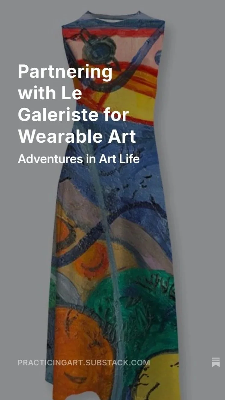 Colorful dress with an abstract painted design featuring various vibrant colors, including blue, green, orange, yellow, and red, hanging against a plain wall.