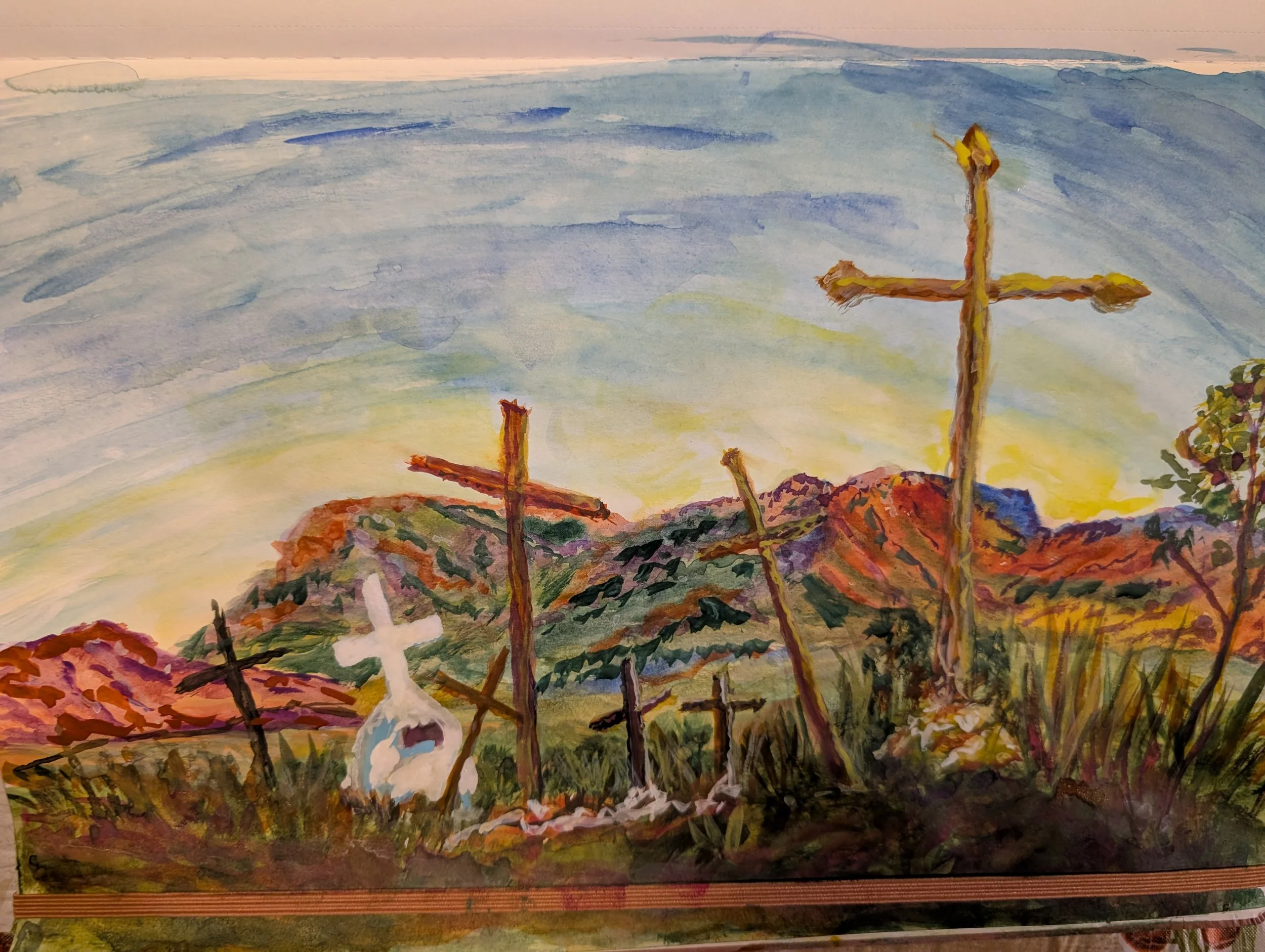 Watercolor painting of several crosses on a hillside with mountains and a colorful sky in the background.