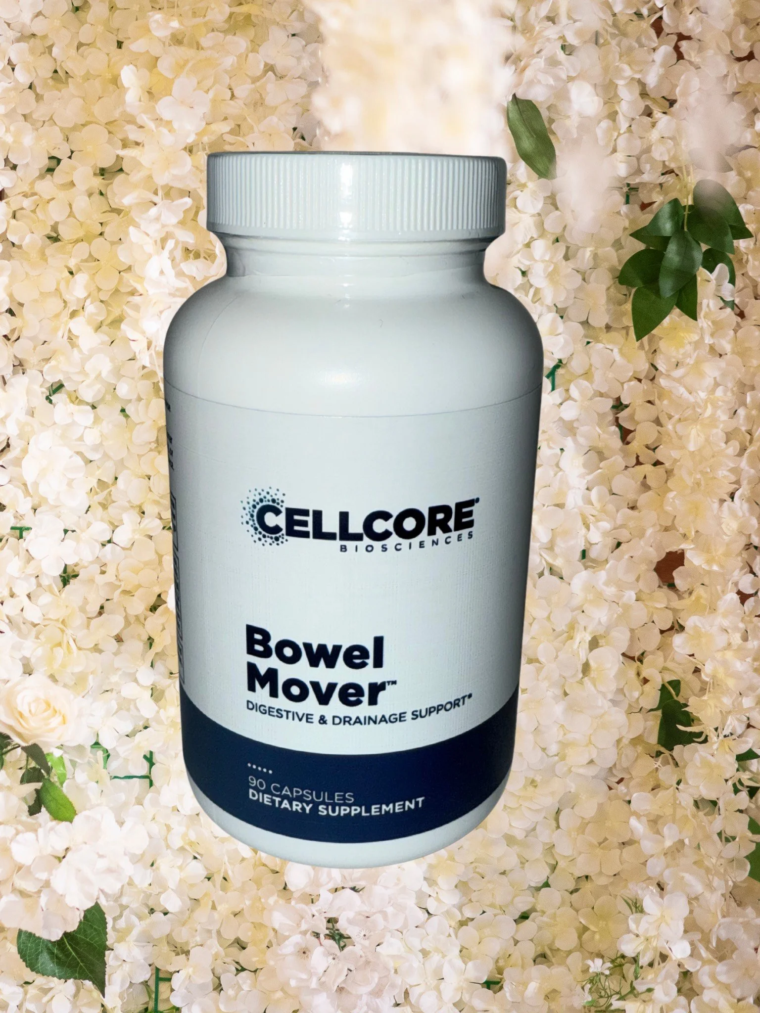 Bottle of Cellcore Biosciences Bowel Mover dietary supplement against a background of white flowers.