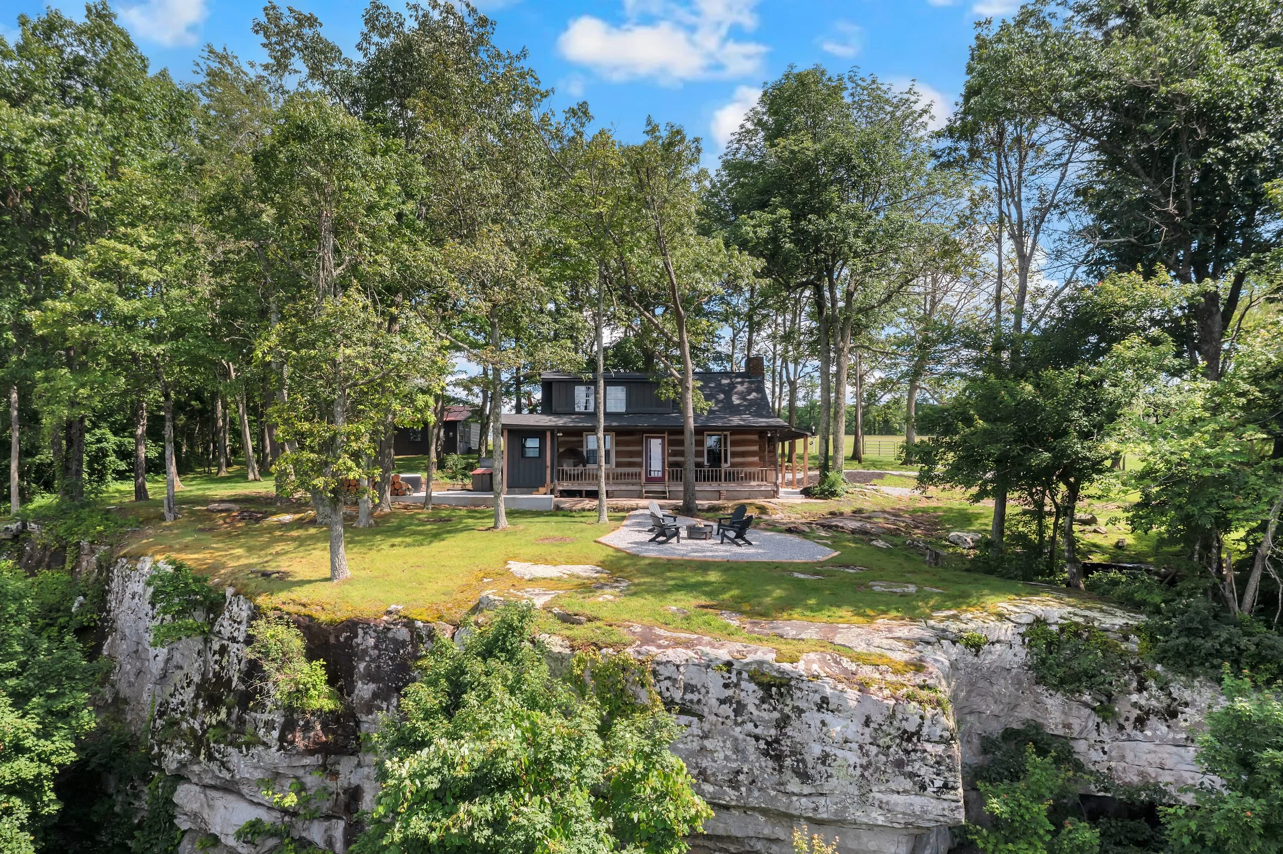 A house on a hilltop surrounded by trees with a patio and outdoor seating area. Gorgeous views.