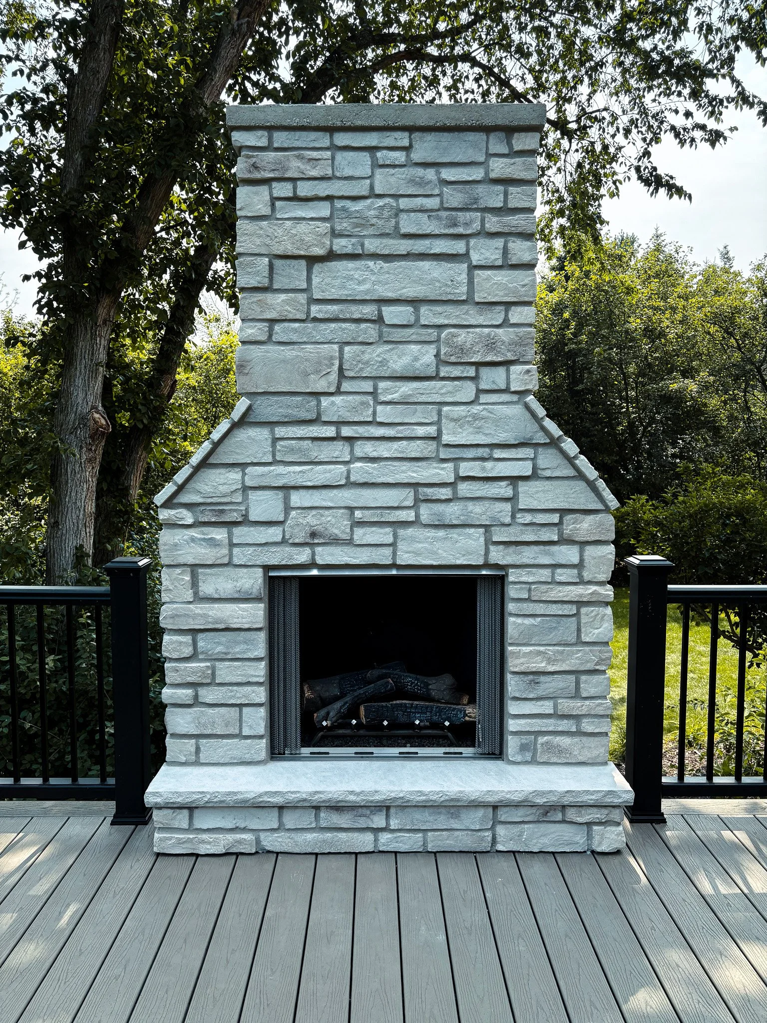 Photo of a custom stone fireplace on outdoor patio created by Revival Homes.