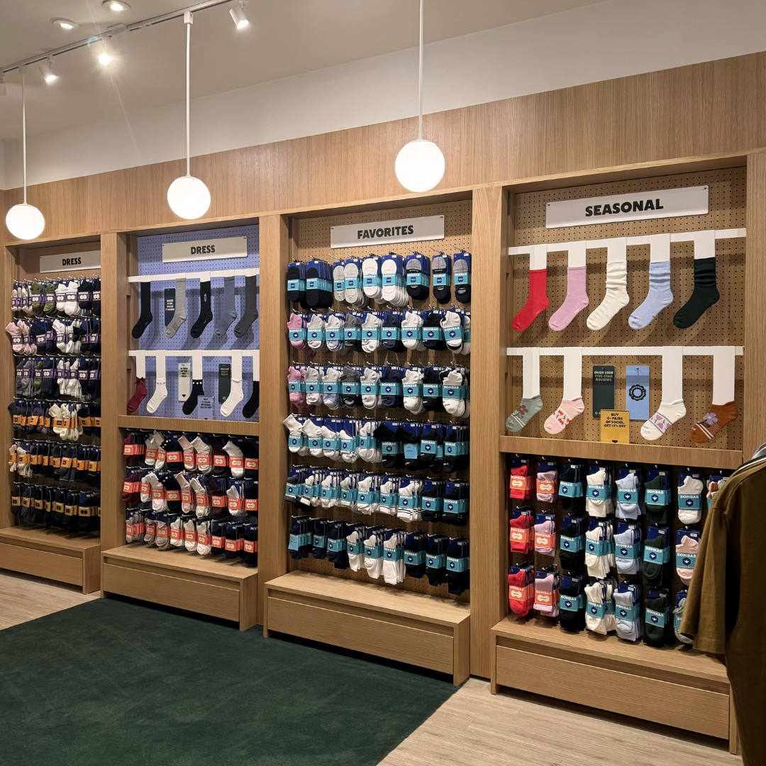 Display of various socks arranged on wooden shelves, pegboards. Retro design. Warm. Inviting. 