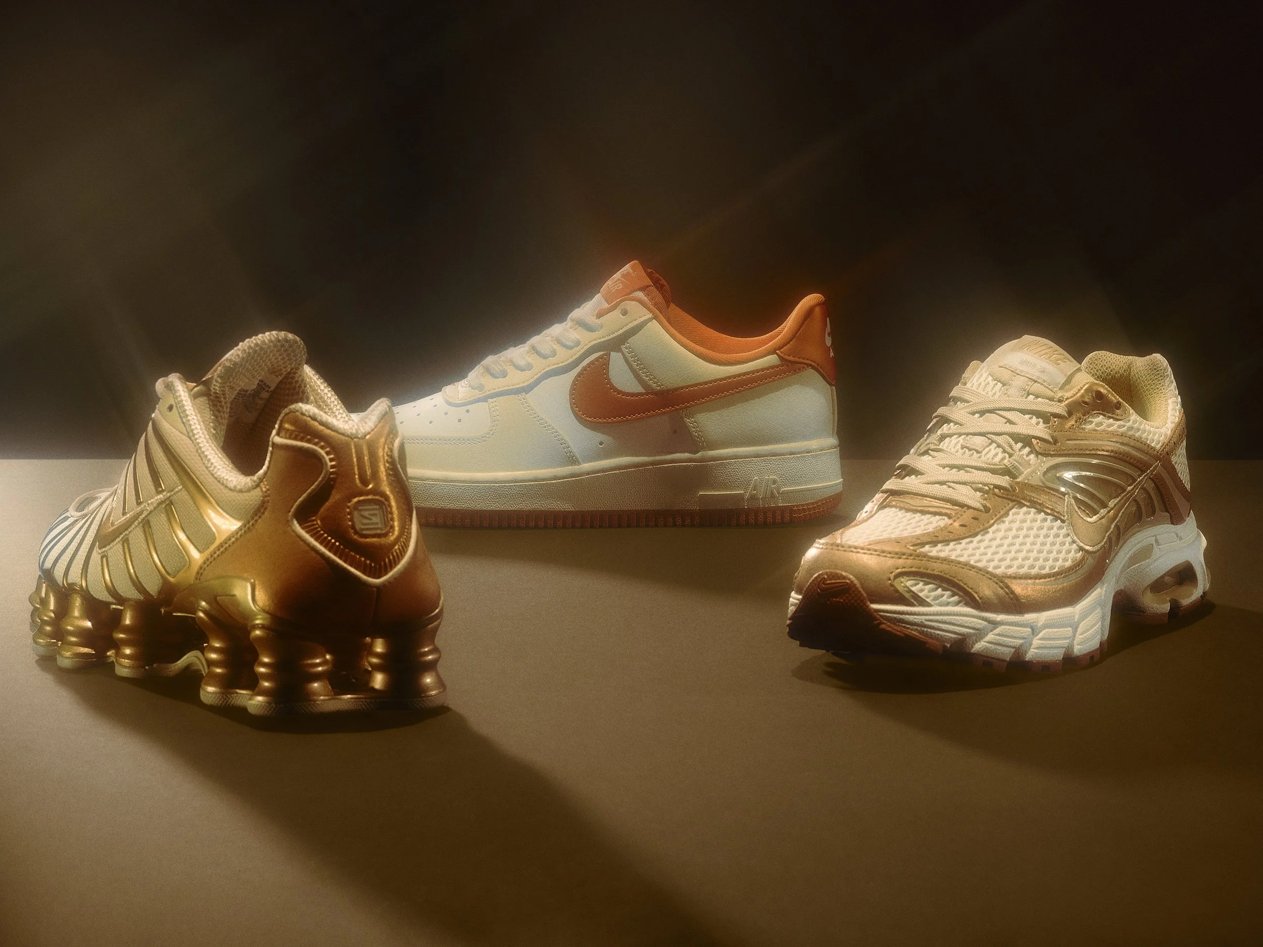 Three pairs of Nike sneakers arranged on a surface with dramatic lighting and shadows.