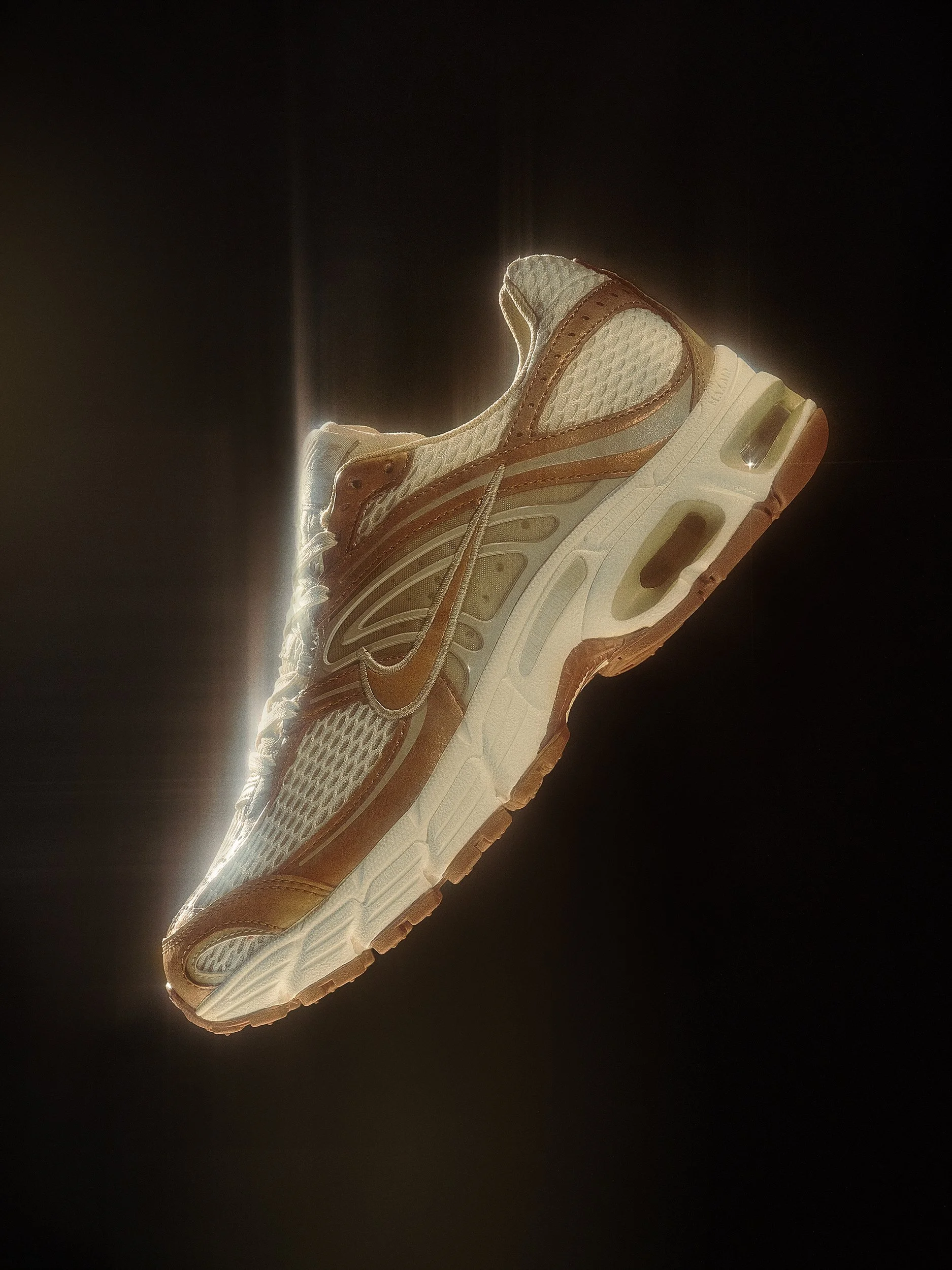A close-up of a modern athletic running shoe with a beige and white mesh upper and brown accents, isolated against a dark background.