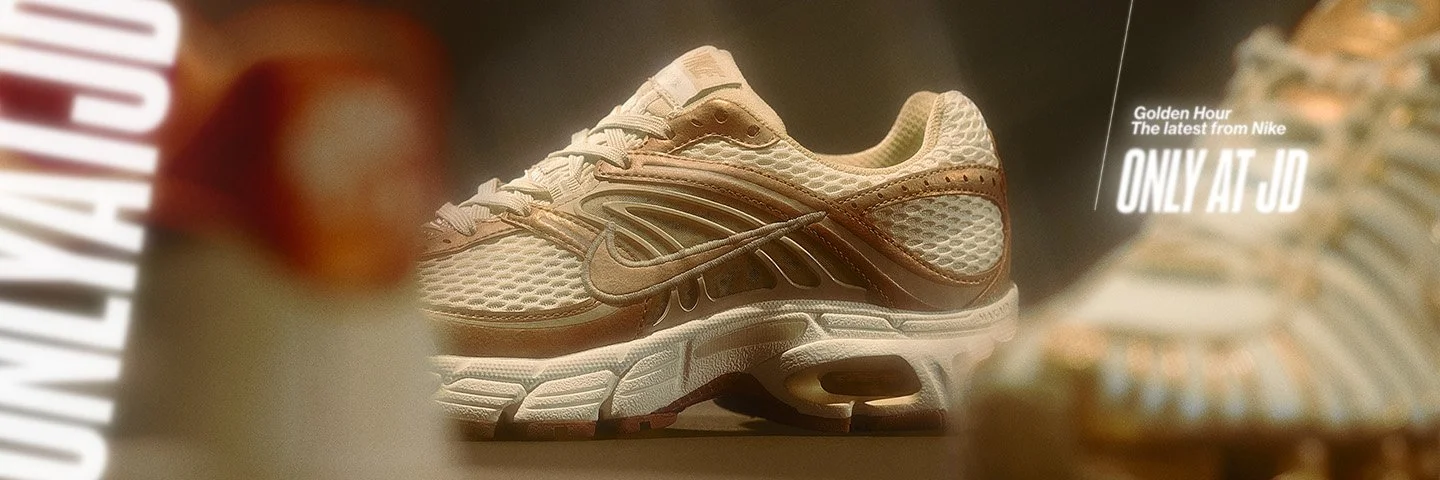 Close-up of a beige and brown Nike sneaker displayed on a reflective surface.