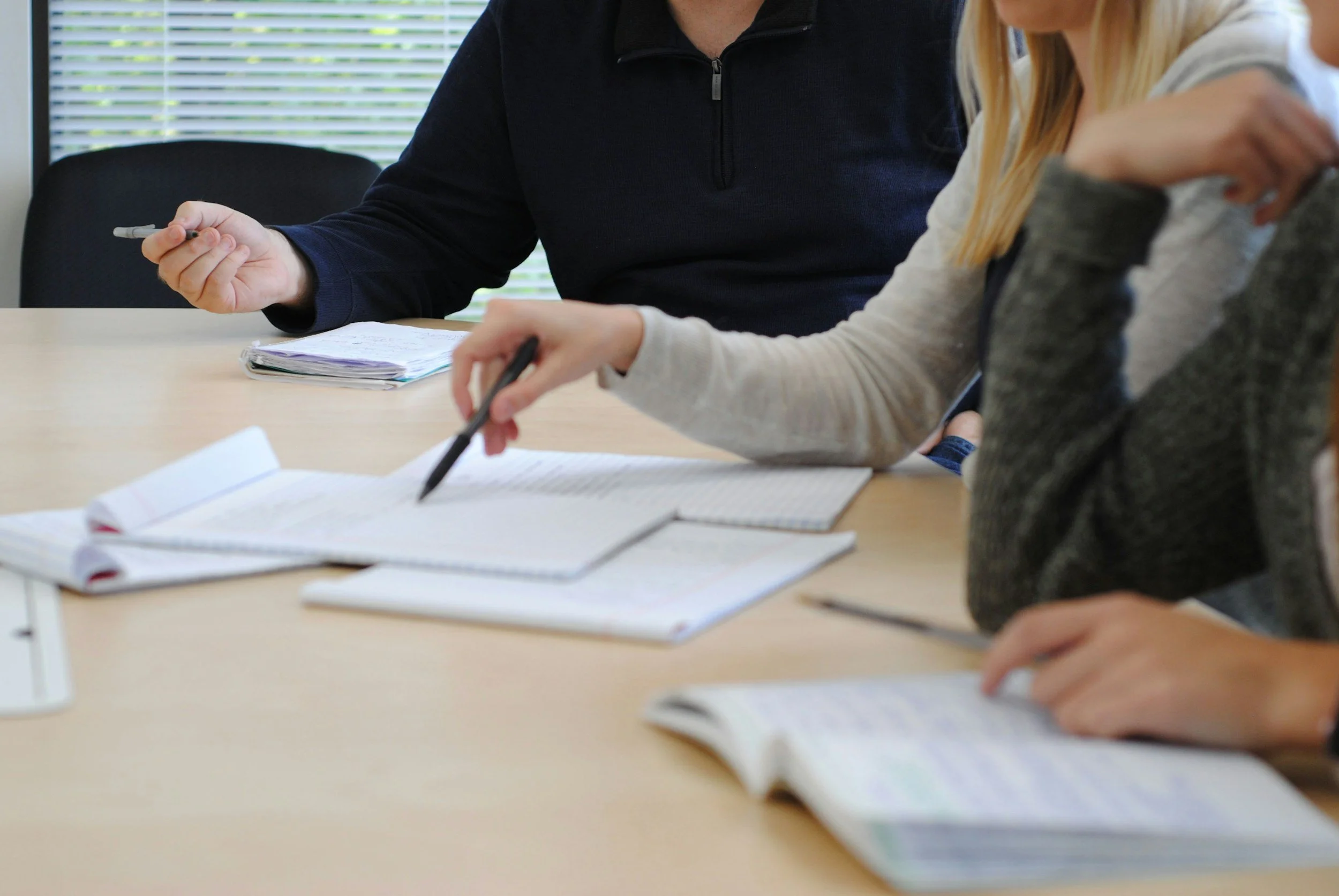 Small group in discussion around a table with notebooks and pens.