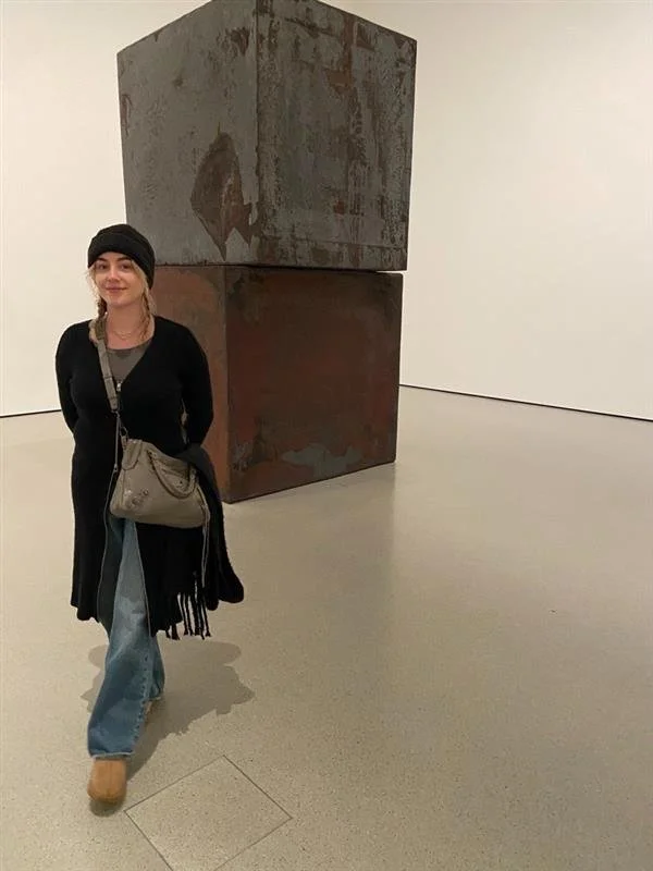 A woman standing next to large modern abstract sculptures in an art gallery.