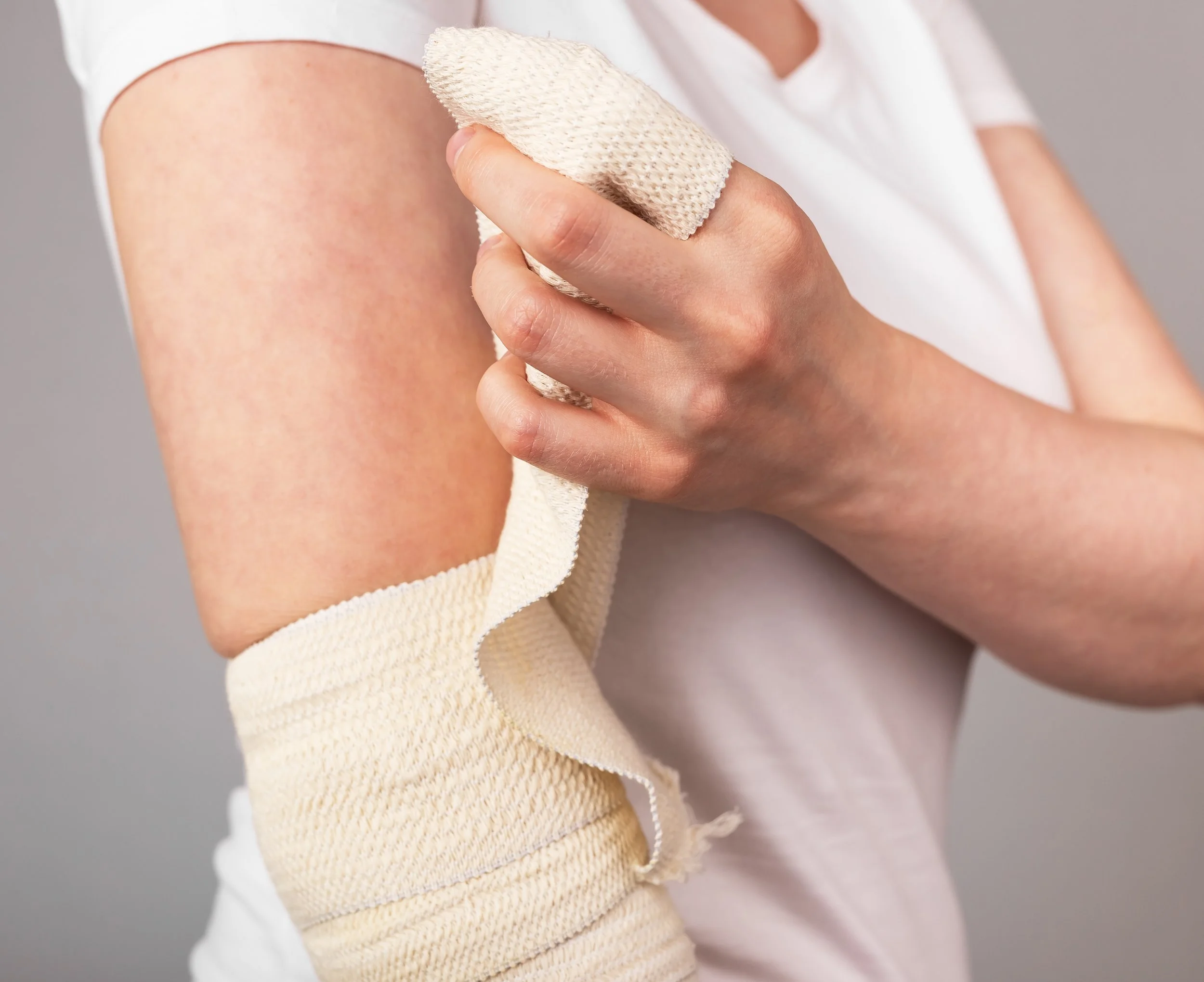 Person applying a cream bandage to their upper arm.
