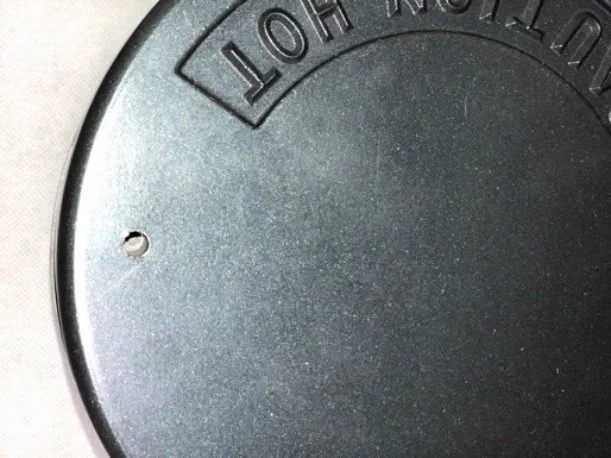 Close-up of a black metal object with the words 'LOT NOT IN' embossed on the surface, and a small hole on the left side.