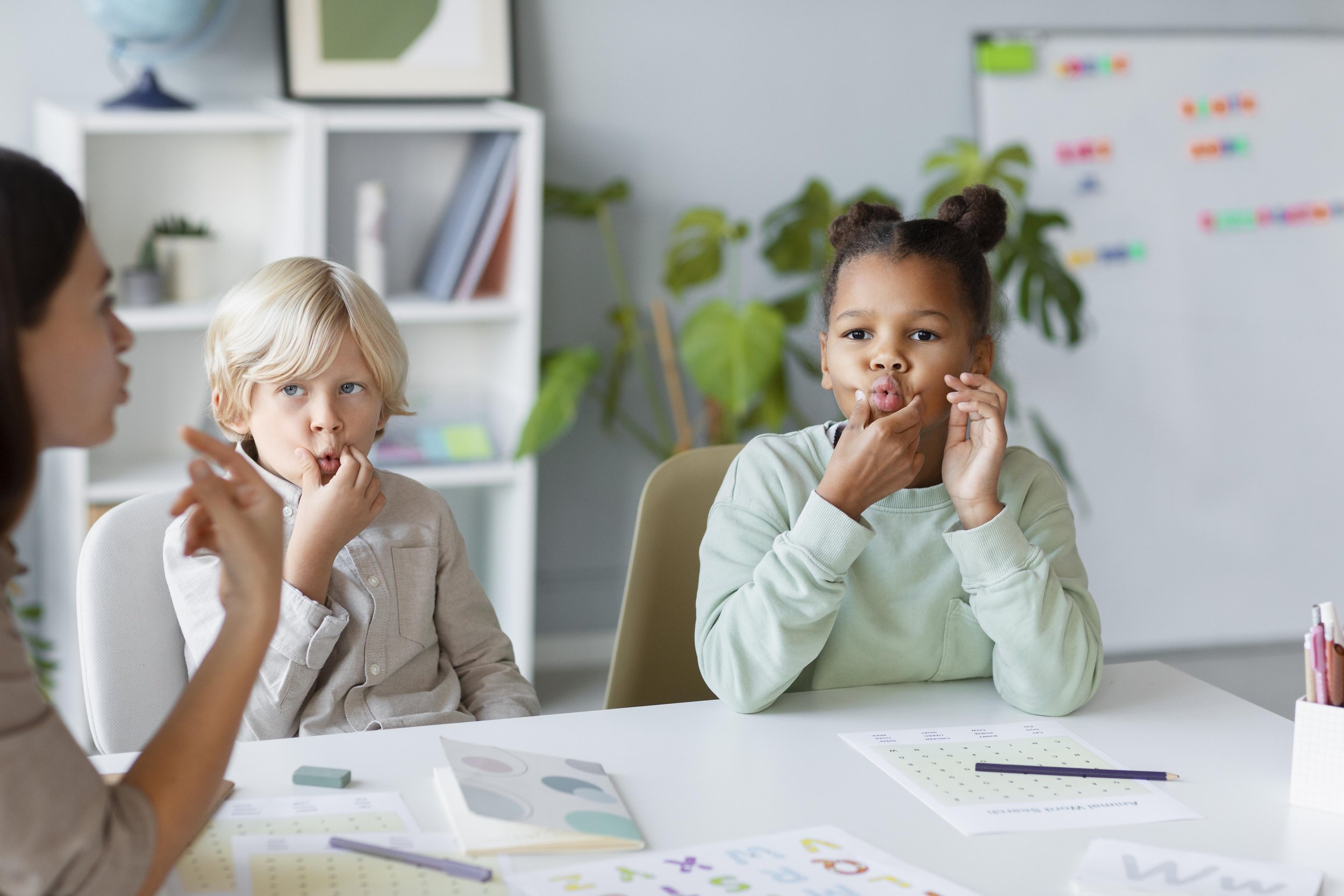 A child sitting on an orange surface, playing with colorful foam animal-shaped puzzles learning language development as a preschooler with a language delay and speech delay in Bellingham, Washington
