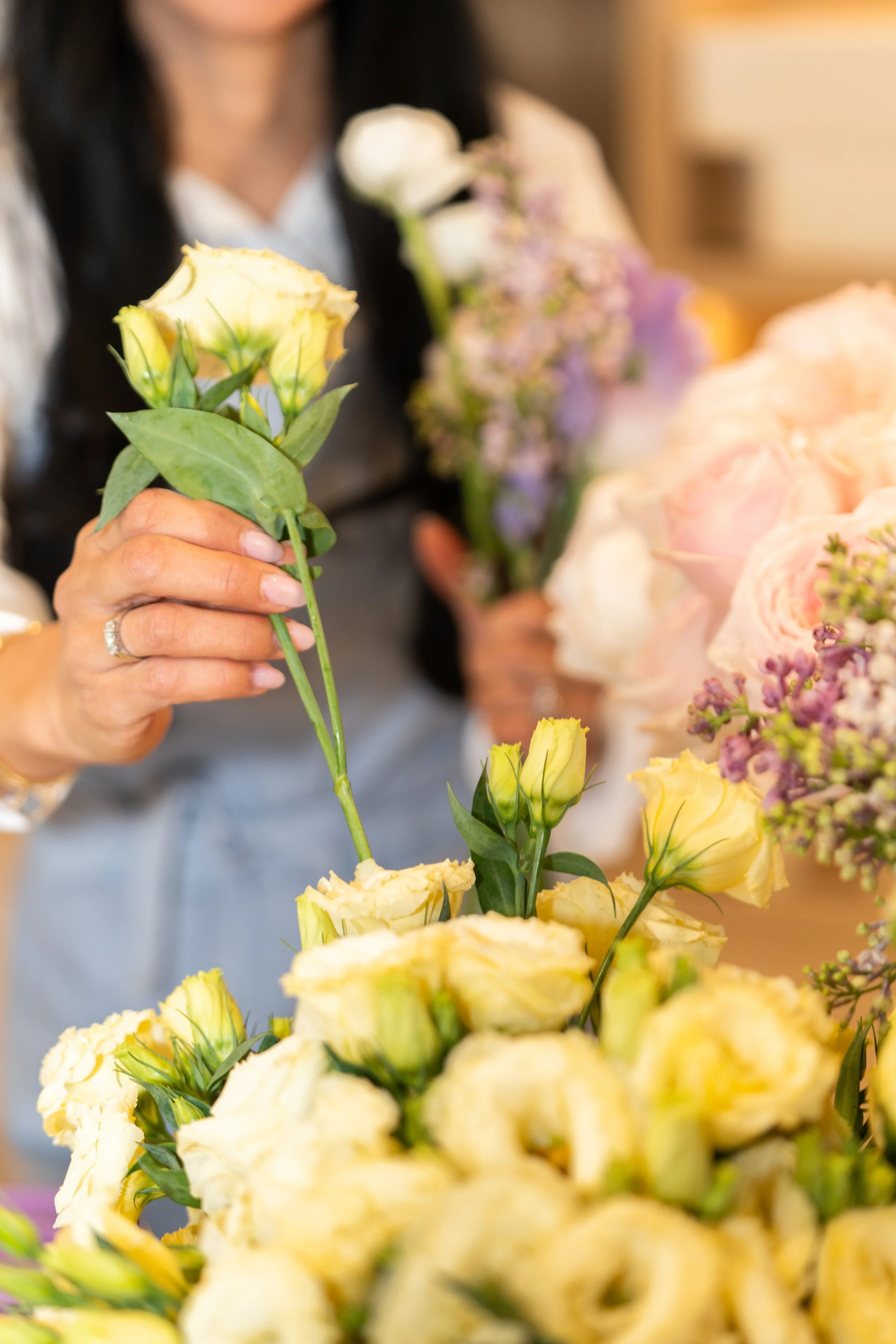 People arranging a bouquet of yellow and white flowers in a floral shop.