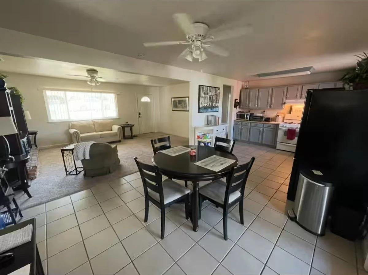 Open-concept living room and kitchen with a dining table, chairs, a sofa, a ceiling fan, and kitchen cabinets and appliances.
