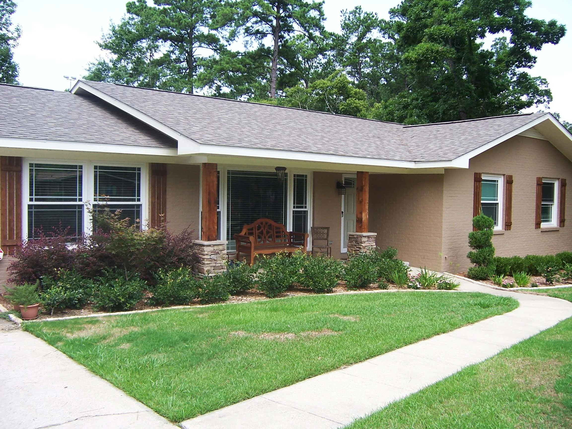 White framed replacement windows with shutters on a traditional home.