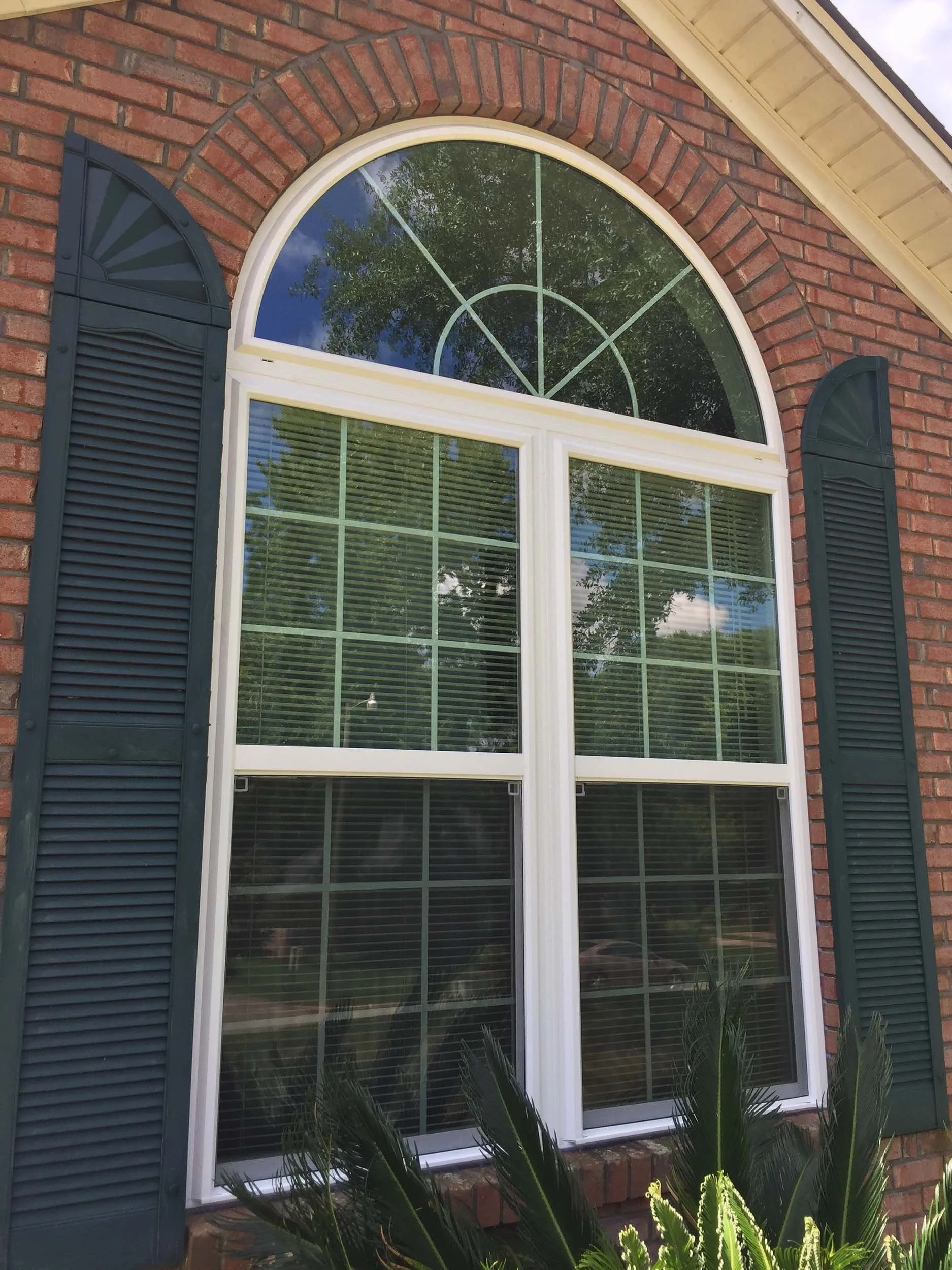 Arched replacement window installation with brick trim.