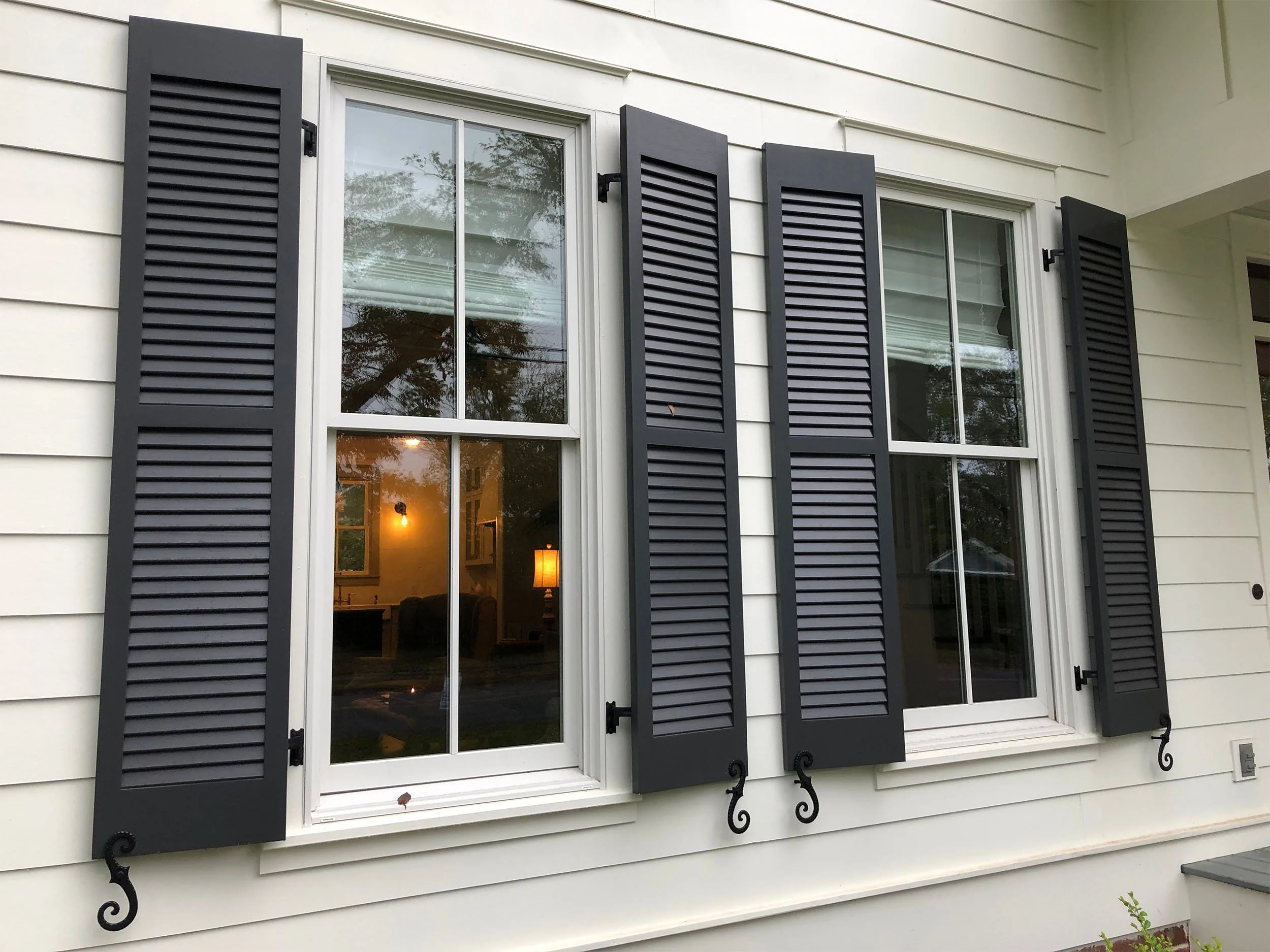 Replacement windows installed on a home with classic shutters and trim.