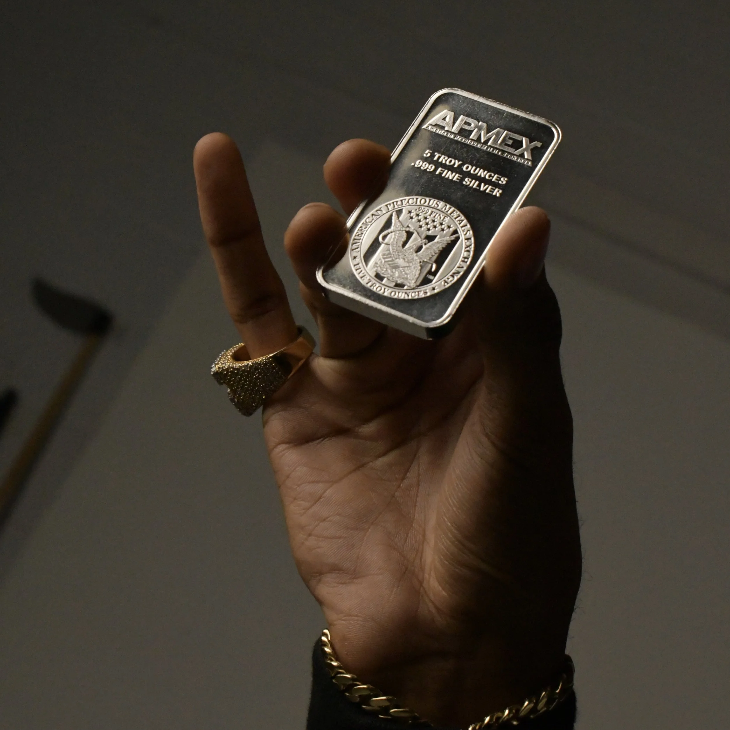 Hand holding a silver bar of 5 troy ounces of .999 fine silver.