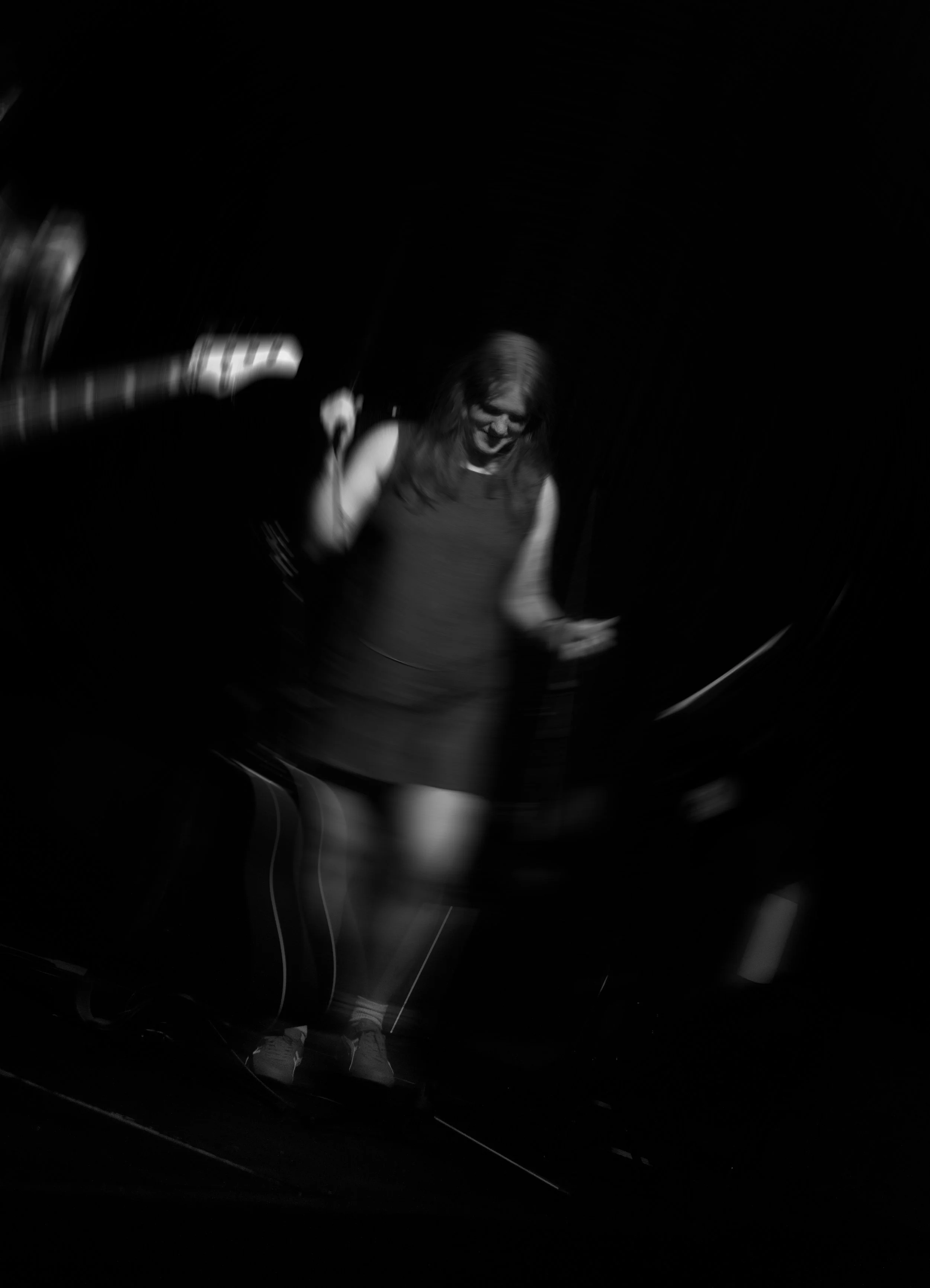 A woman singing into a microphone on a dark stage, with a blurred background and spinning motion effect.