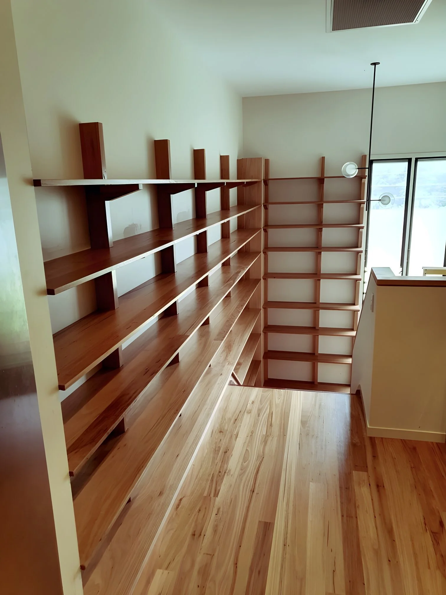 Empty wooden shelves in a corner near a window with sunlight