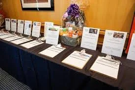 Table with pamphlets, brochures, and informational flyers arranged in a row, with a basket of purple and white flowers in the background.