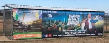 Large billboard with promotional content, including text about results and excellence, and contact information, set on a fence in an outdoor area.