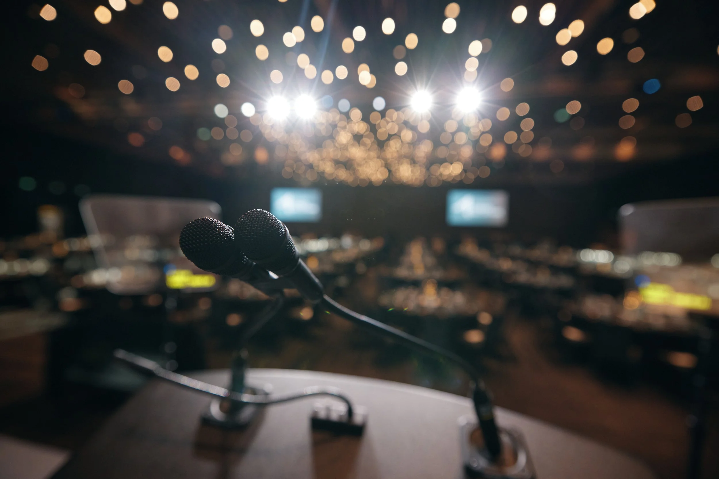 Microphones on a desk in front of an audience during a conference or presentation