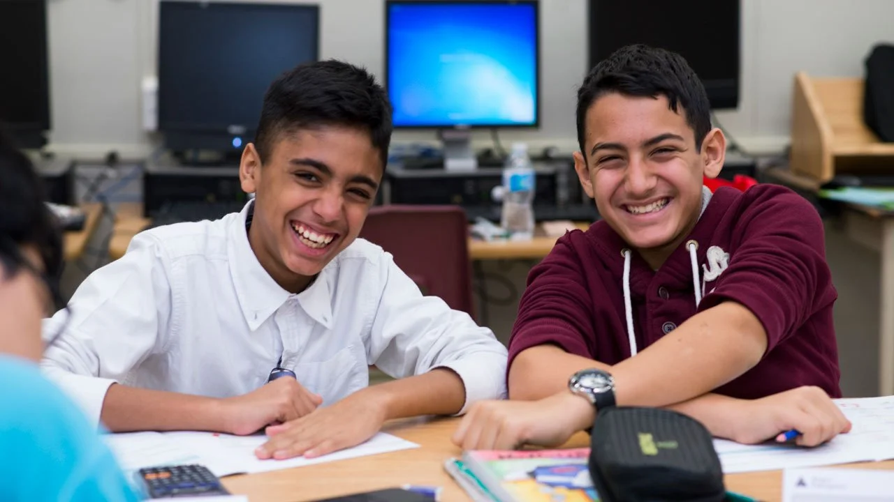 Students smiling at a table during a JA (Junior Achievement) Southern Alberta classroom program