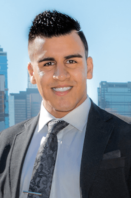 Former JA (Junior Achievement) Southern Alberta student smiling outdoors with a city skyline in the background