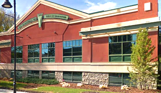 Exterior of a red brick school building with large windows and a sign that reads 'University of Upland'.