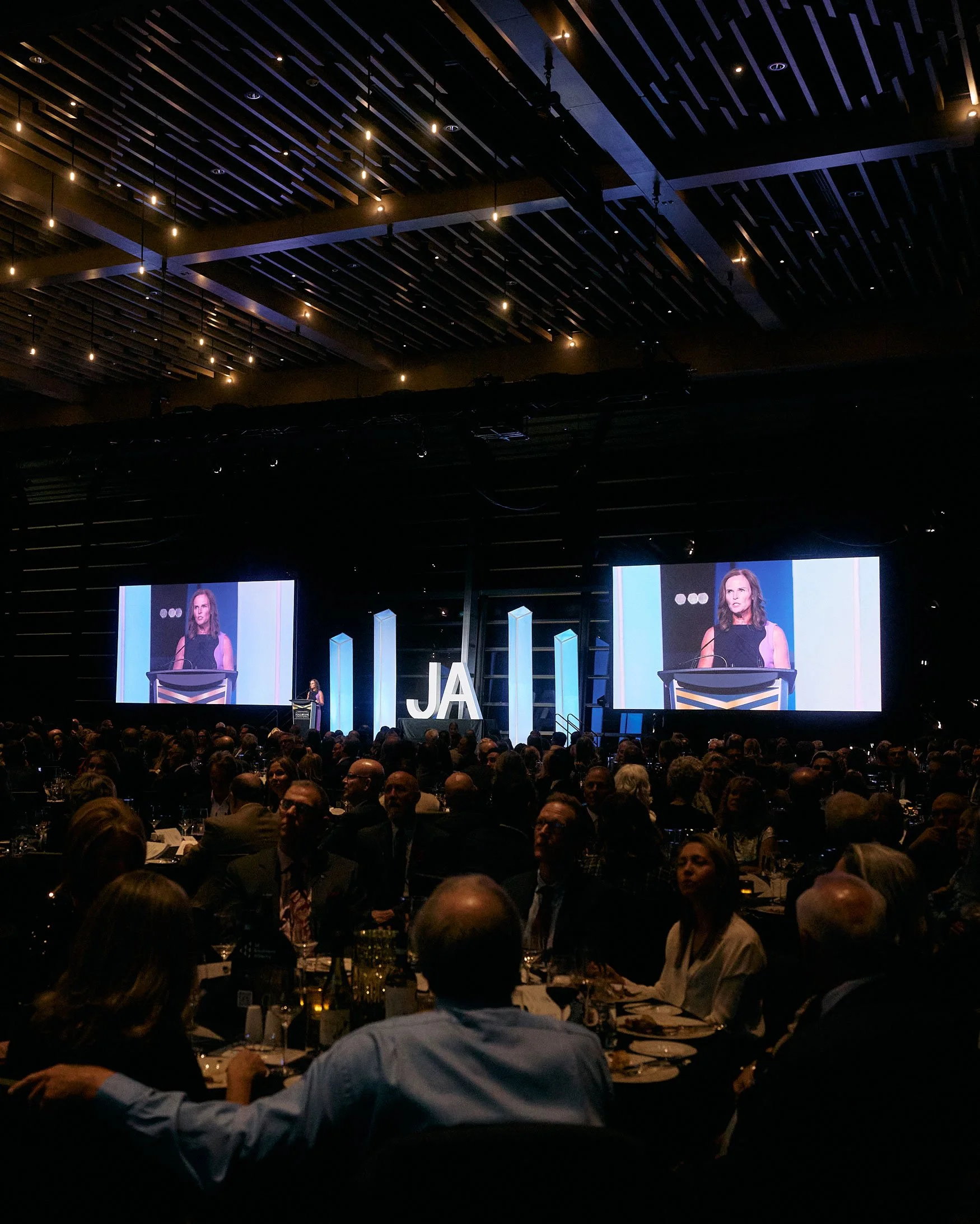 Speaker presenting to a large audience during a JA (Junior Achievement) Southern Alberta event