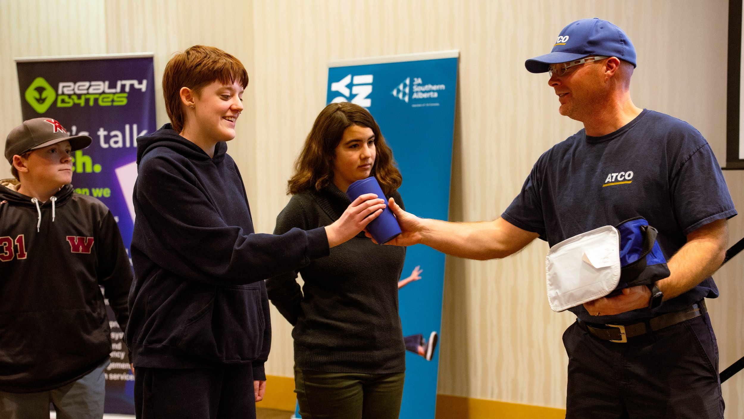 Student receiving recognition from a presenter at a JA (Junior Achievement) Southern Alberta event