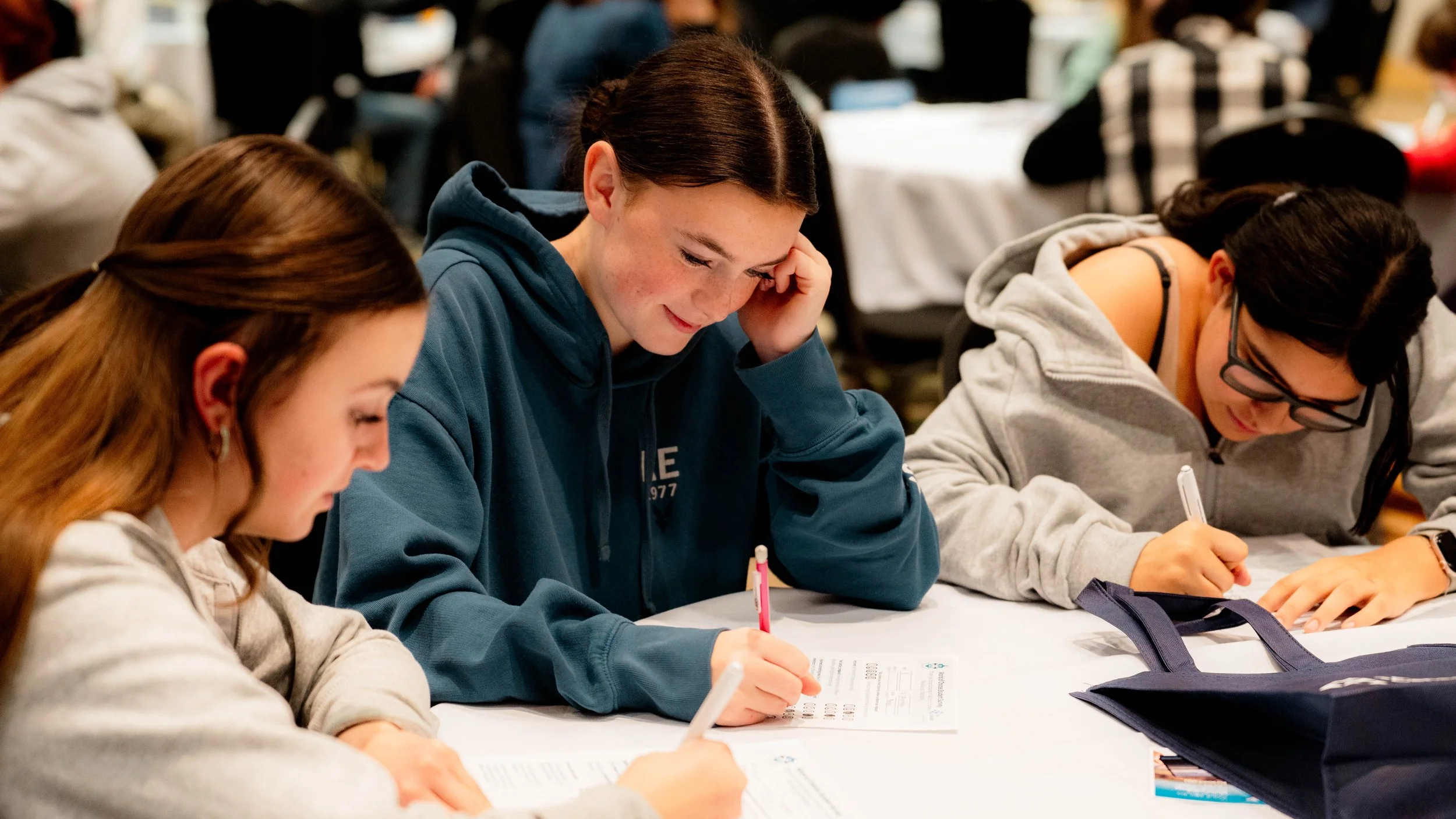 Students sitting at a table, writing and studying during a class or workshop.