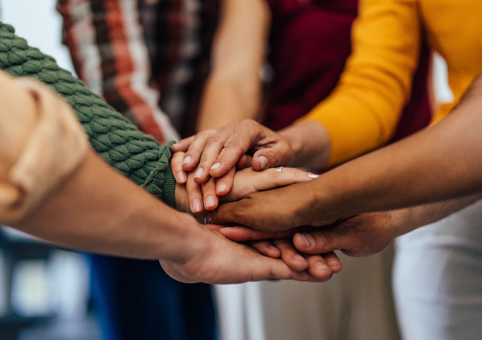 Students stacking hands in a teamwork gesture during a JA (Junior Achievement) Southern Alberta program.