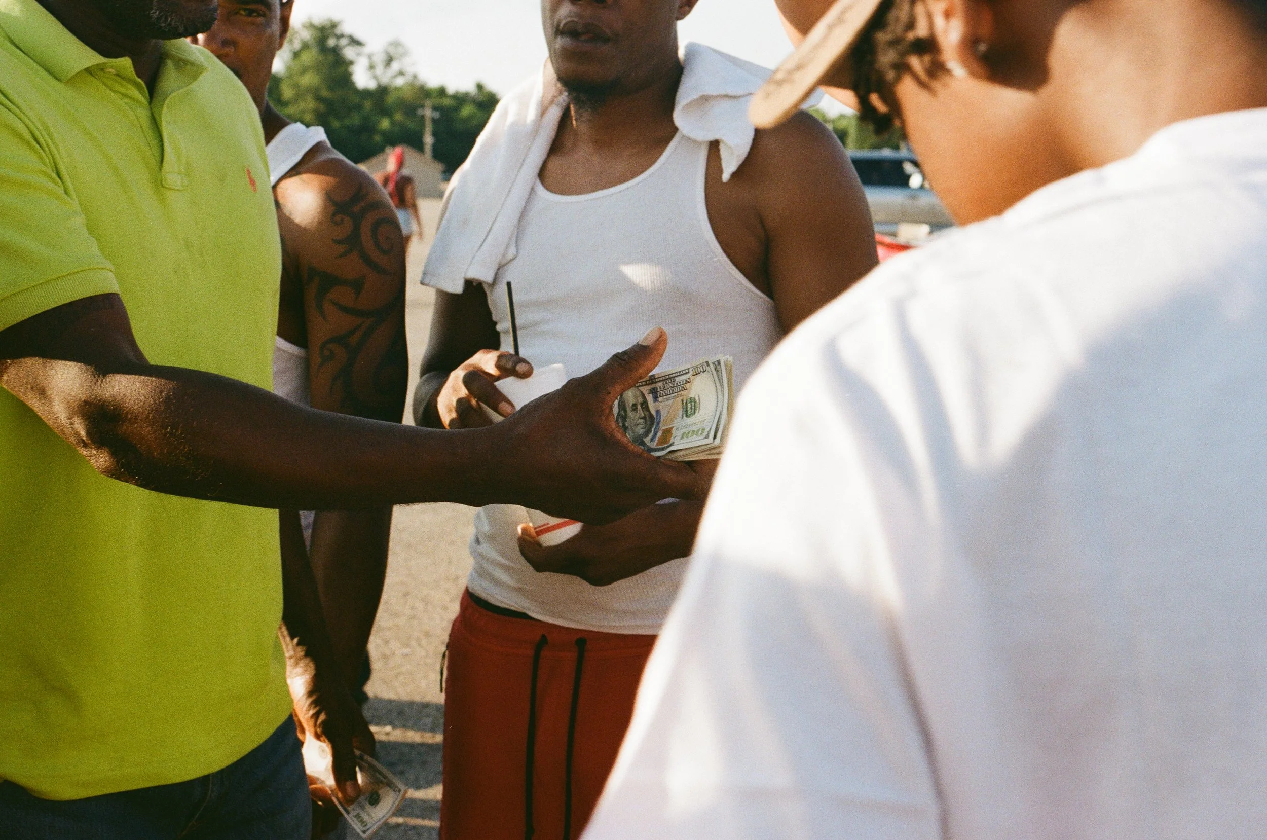 Group of people outdoors, some holding money, engaged in a conversation.