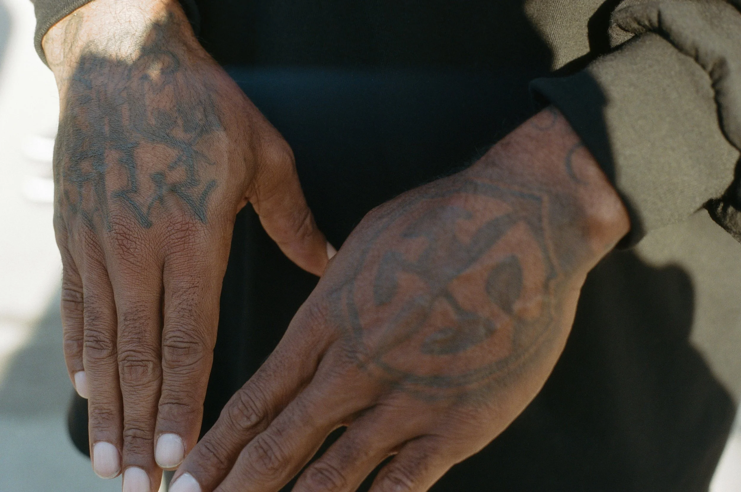 Close-up of hands with tattoos, resting on each other.