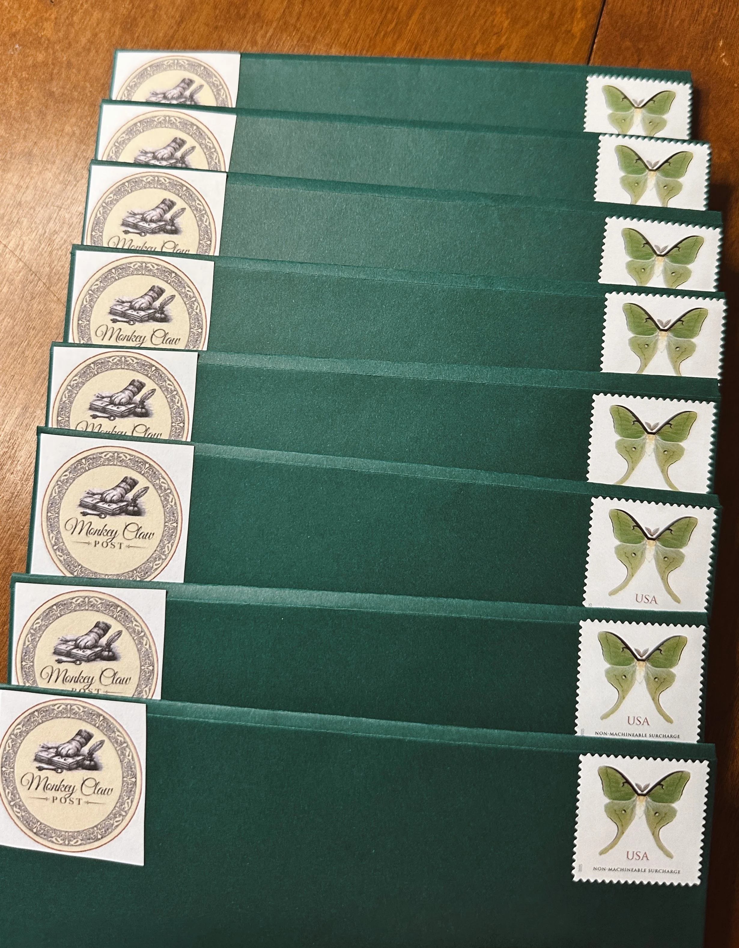 Seven green envelopes with postage stamps, featuring a butterfly design, and a logo of a monkey paw with the text 'Monkey Claw POST'.