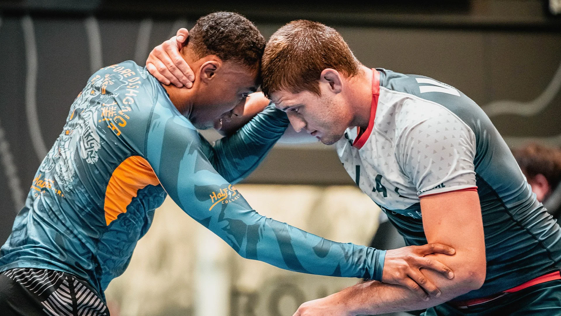 Two male athletes are engaged in a sports injury, with one supporting and comforting the other who appears to be in pain, on an indoor court.