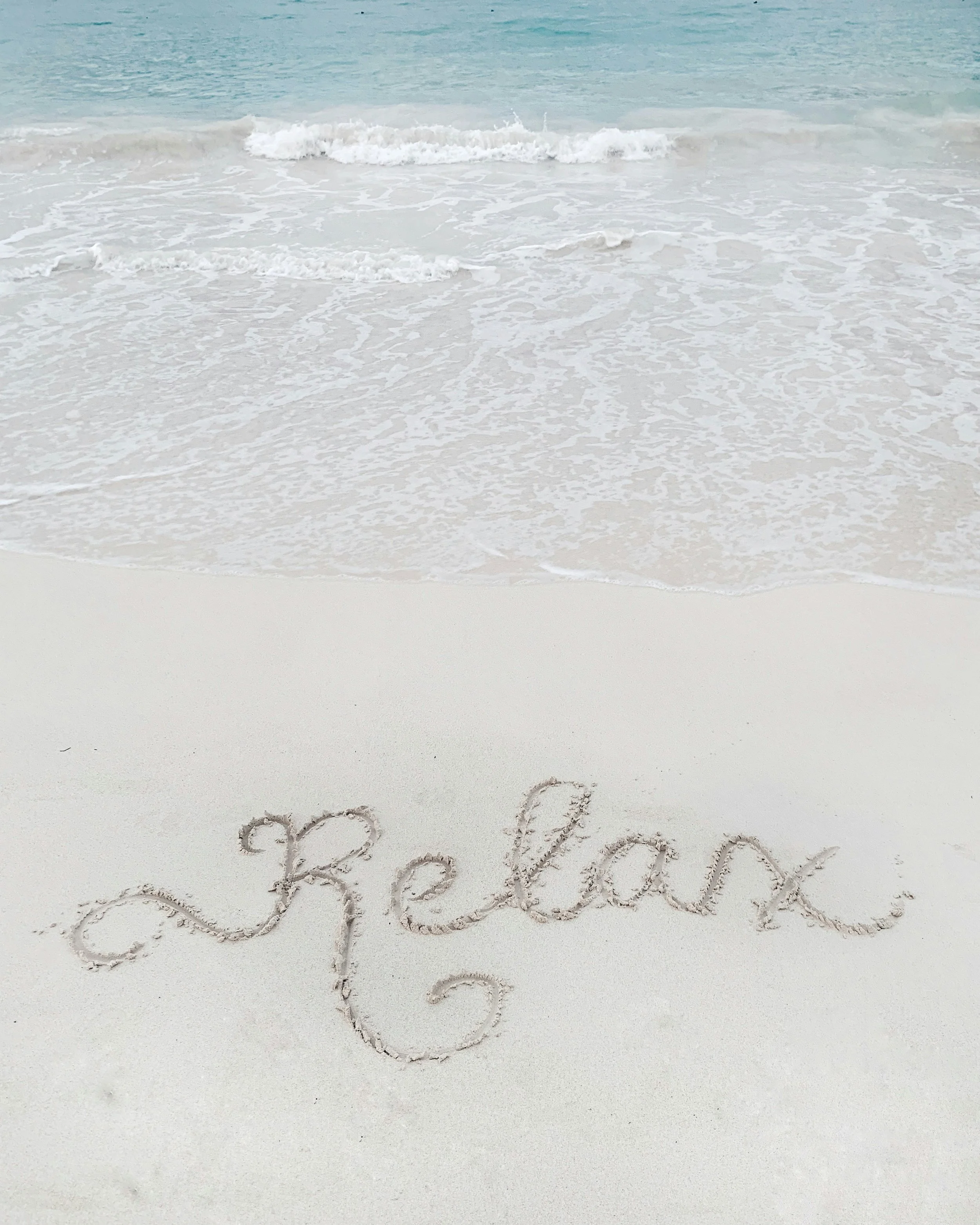 a sandy beach with the word "Relax" written in the sand
