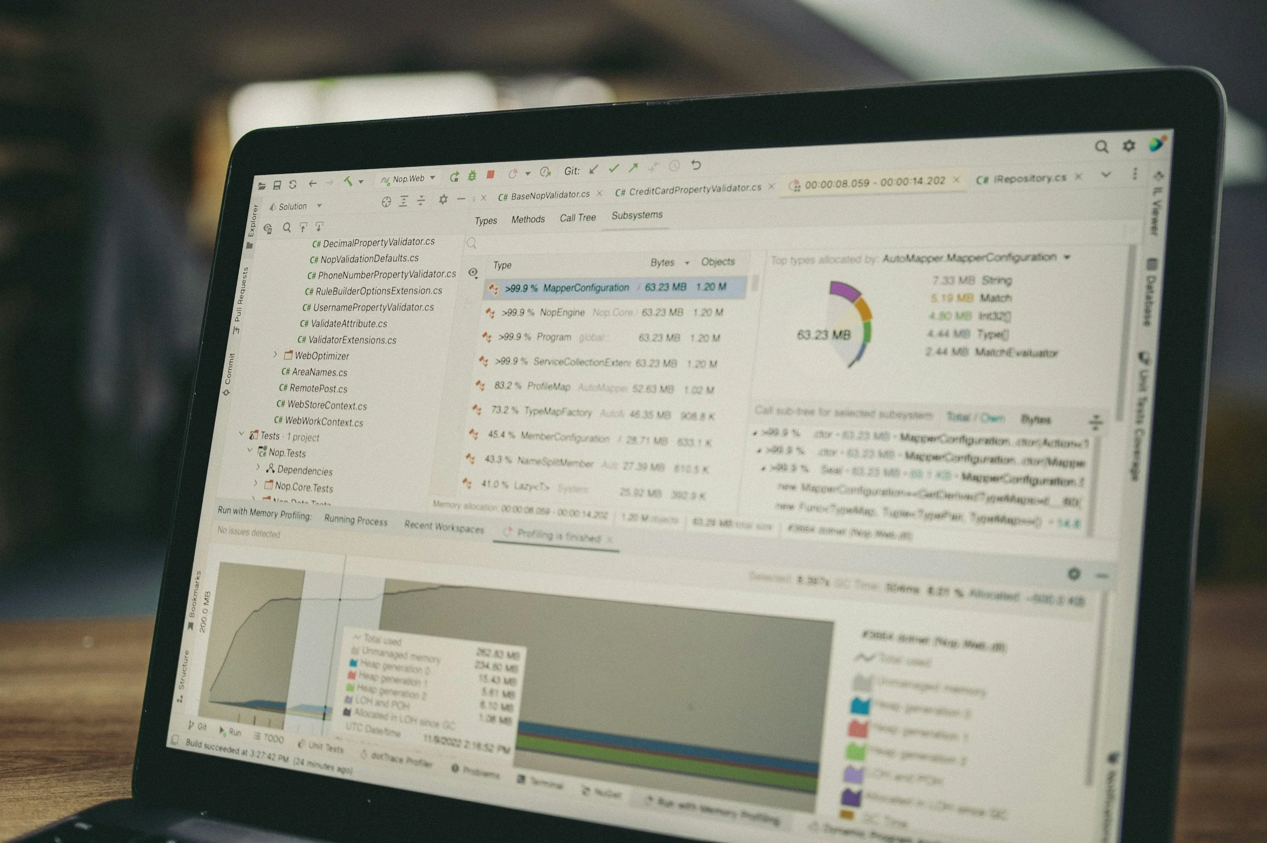 A laptop screen displaying a software development IDE with code, files, and resource monitoring graphs.