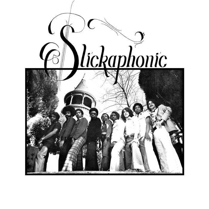 A black-and-white photo of nine diverse people standing outdoors in front of a large house with a tower. The group appears confident and stylish. Above the photo, the word "Slickaphonic" is written in a decorative font.