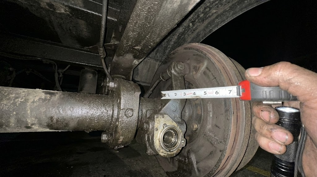 Mechanic performing under-chassis brake measurement and S-cam check for 90-day BIT inspection compliance