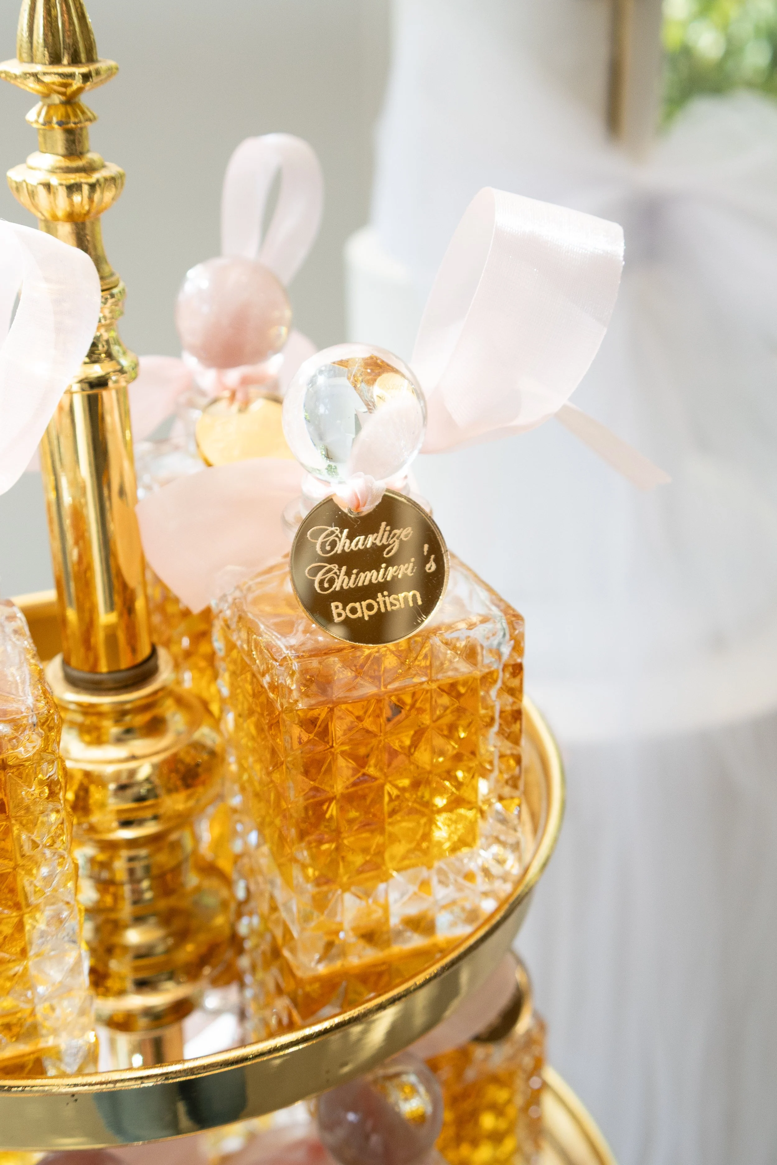 Close-up of an ornate gold and glass candle holder with a jelly-like amber decorative item, a clear glass globe, and a gold circular tag.