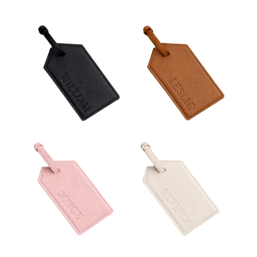 Four luggage tags in black, brown, pink, and white, each with a strap, arranged on a white background.