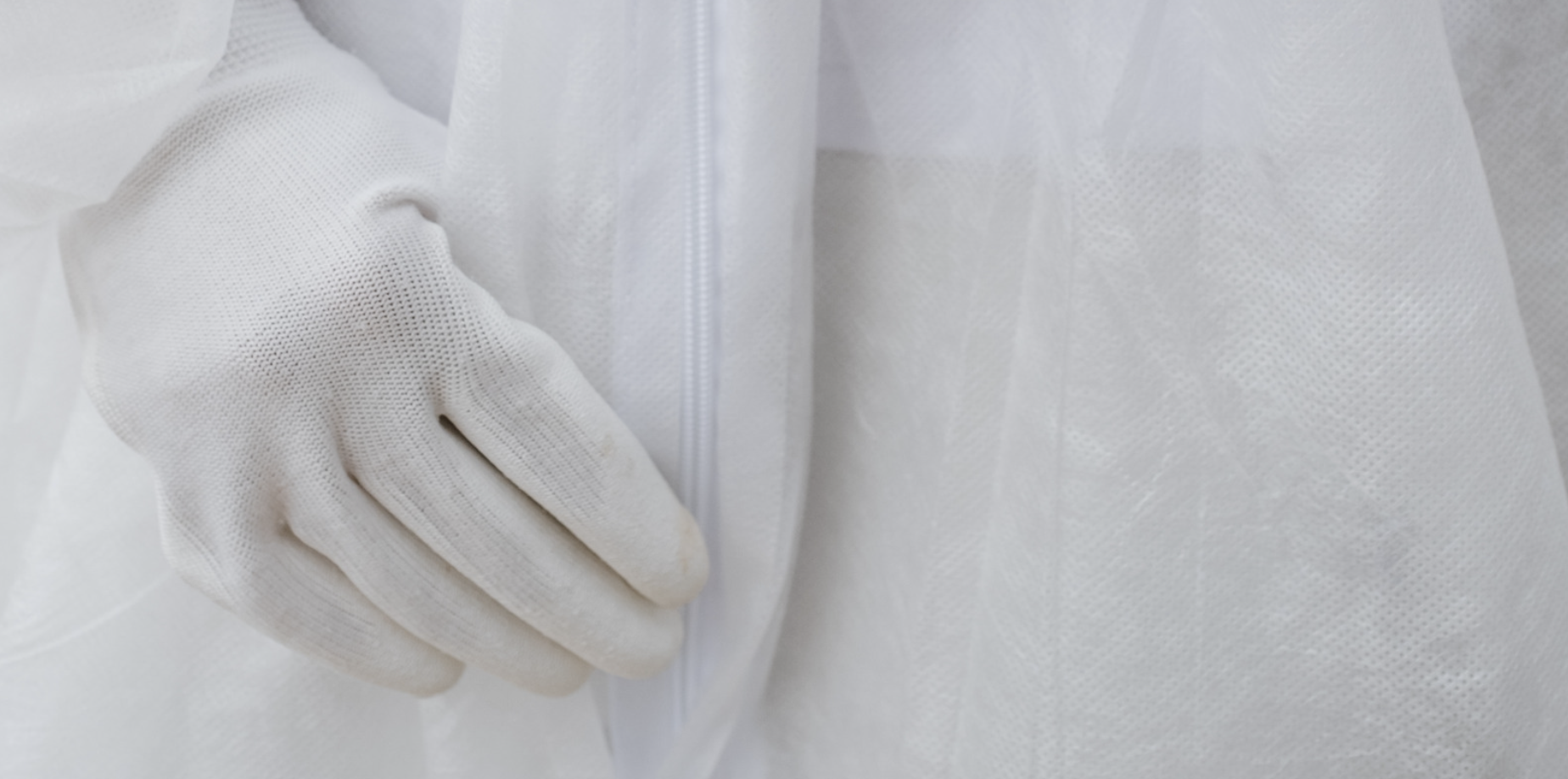 Close-up of a person wearing a white protective suit and a matching glove.