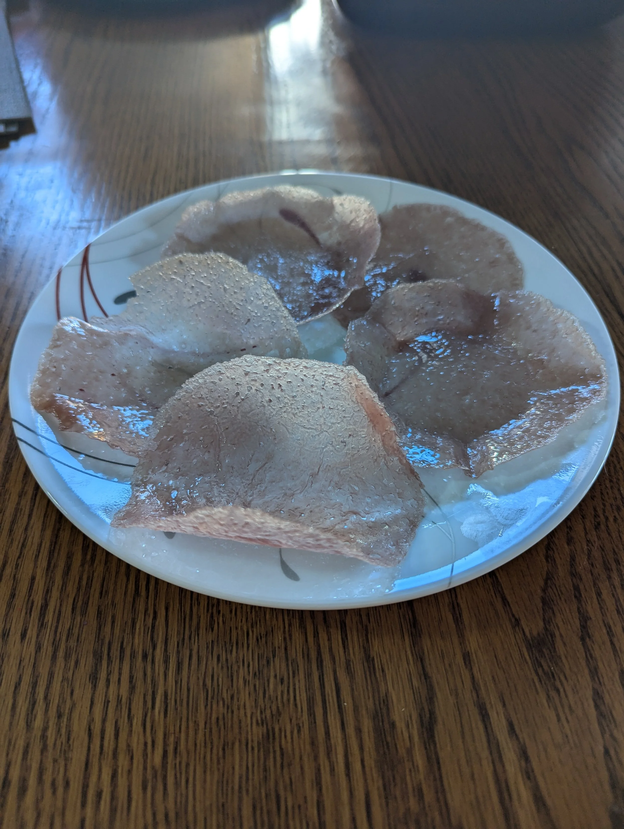 Plate of dried pork rinds on a wooden table.