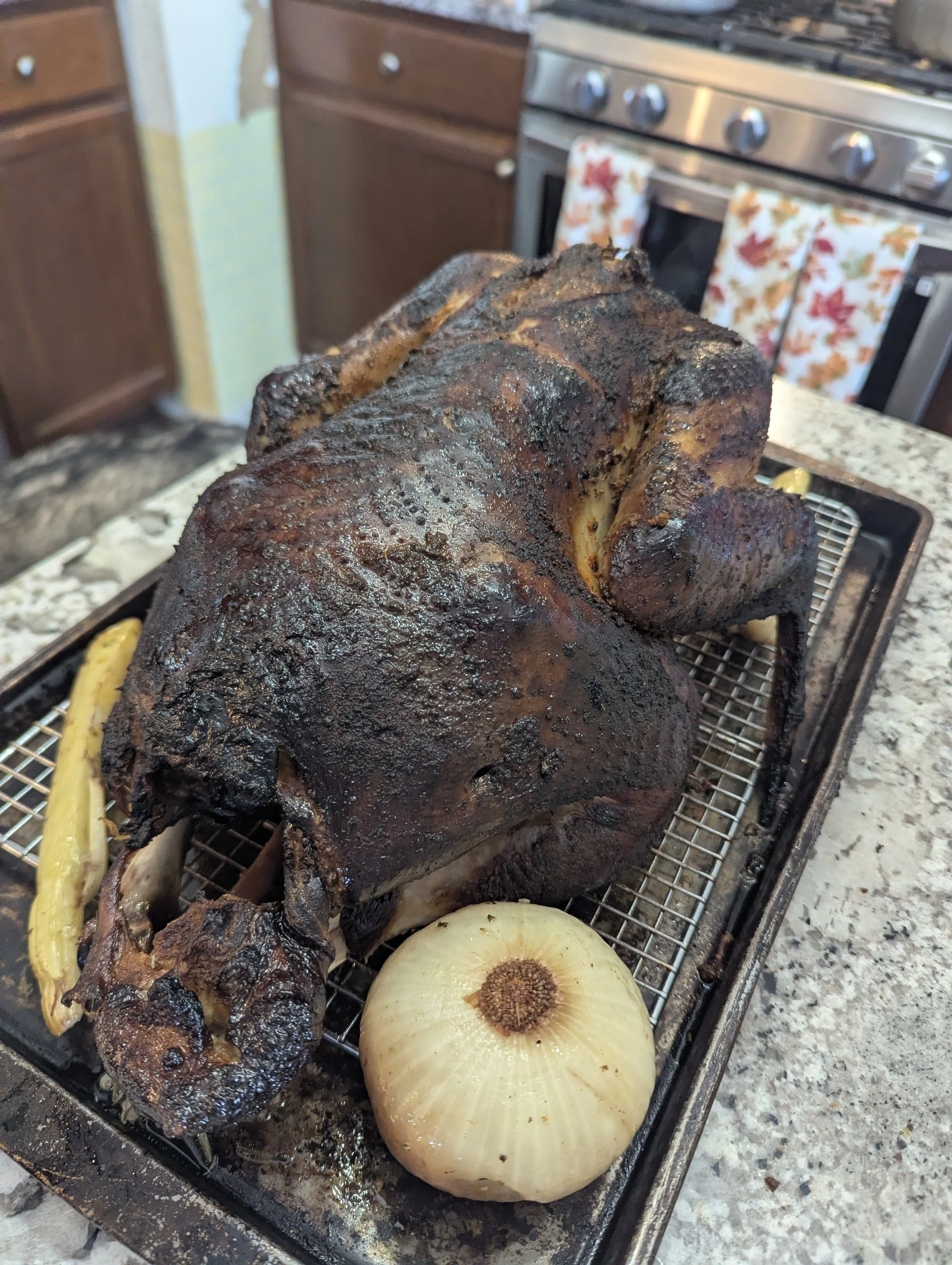 Cooked whole pig on a roasting rack with onion and lemon slices in a kitchen.